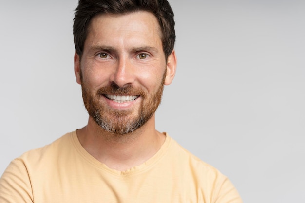 Photo portrait of middle aged smiling bearded man looking at camera isolated on gray background