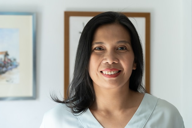 Portrait of middle aged smiling woman with black hair at home