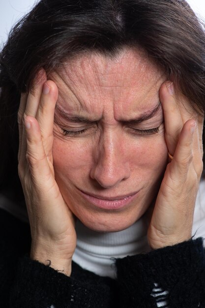 Portrait of middle aged woman touching her temples feeling stress