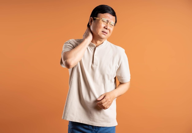 갈색 배경에 포즈를 취하는 중년 아시아 남자의 초상화