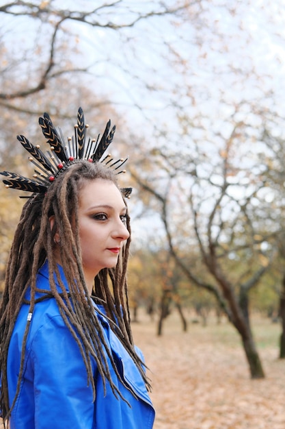 Photo portrait of a middleaged woman in dreadlocks and a hoop on her hair with feathers