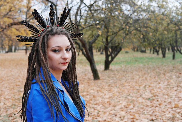 Portrait of a middleaged woman in dreadlocks and a hoop on her hair with feathers