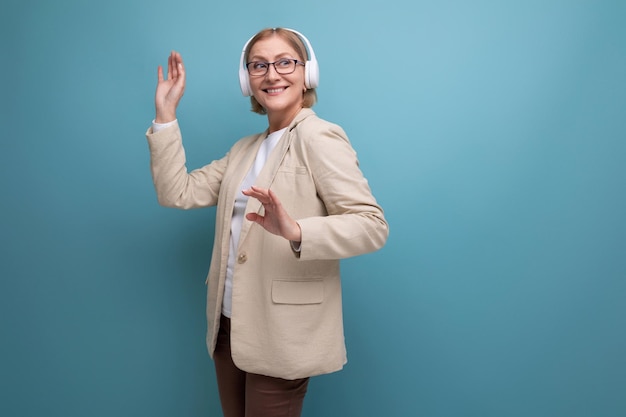 Portrait of a middleaged woman in a jacket enjoying music in headphones on a studio background