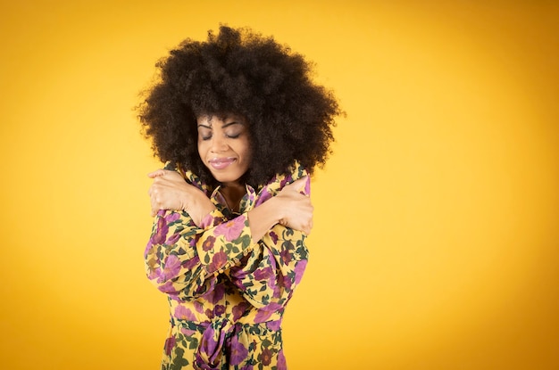 The portrait of a mixed afro dark skinned woman, with her eyes closed and hugging