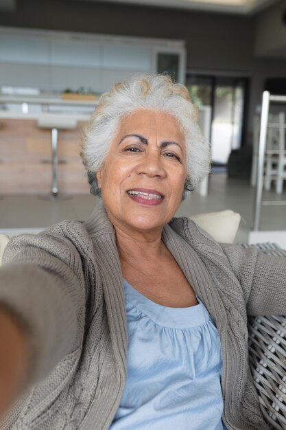 Portrait of mixed race senior woman sitting on sofa making video call