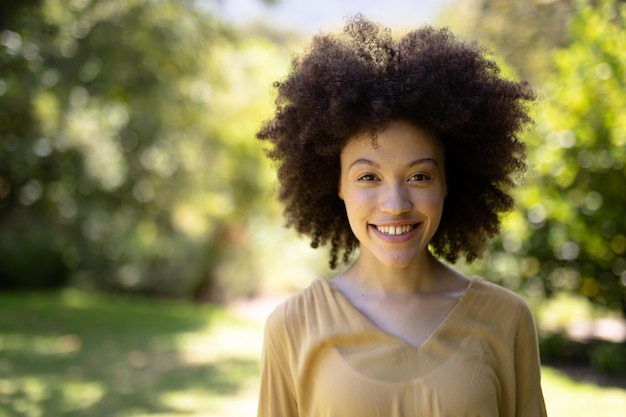 Portrait of a mixed race woman enjoying her time at the garden, looking at the camera and smiling, on a sunny day