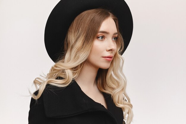 Portrait of a model girl with gentle makeup and a black hat, isolated on white studio background