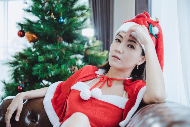 모델 섹시 산타 여자의 초상화 크리스마스 개념에 집에 갈색 소파에 포즈.