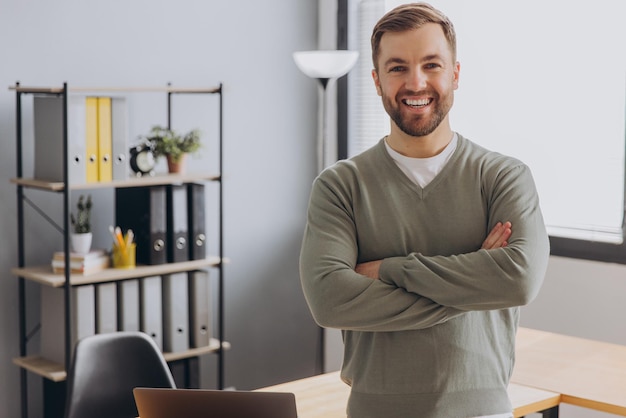 Foto ritratto di un uomo d'affari moderno con una camicia grigia che sorride con i denti sani in ufficio