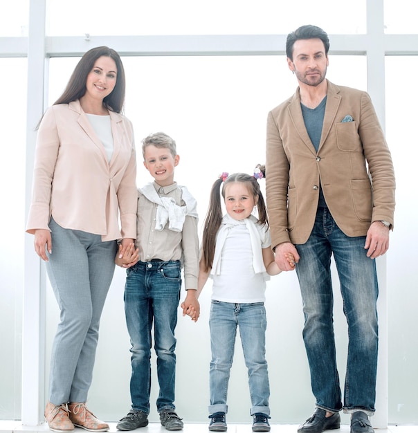 Portrait of a modern family standing near a large window photo with copy space