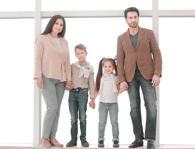 Portrait of a modern family standing near a large window