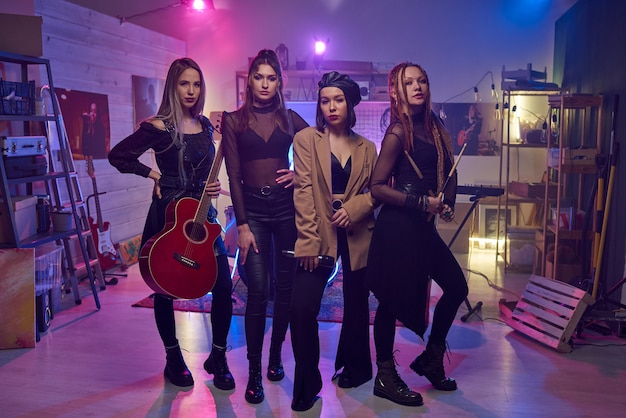 Portrait of modern female musical band looking at camera during their performing in nightclub