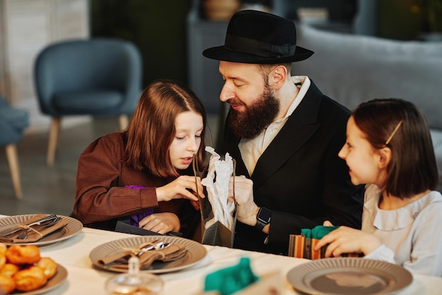 Foto ritratto di famiglia ebraica moderna che condivide regali con i bambini a tavola in un ambiente domestico accogliente