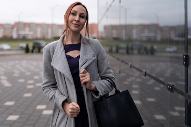 Portrait of modern mature businesswoman next to office building