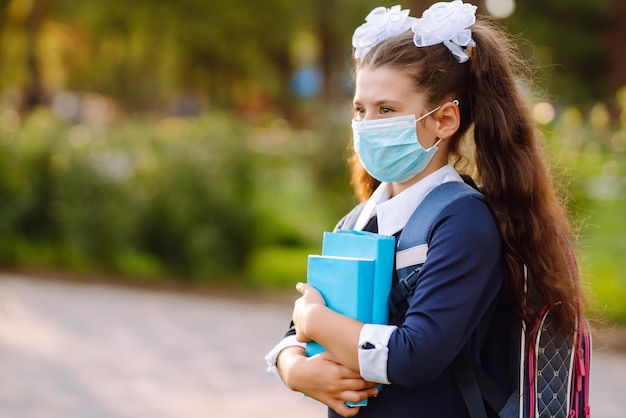 Portrait of modern pupil with book Schoolgirl wearing medical face mask health protection from virus