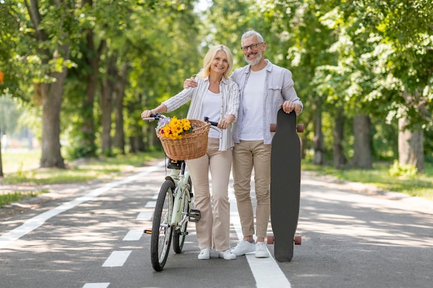 Портрет современных пожилых людей на велосипеде и скейтборде, расслабляющихся в городском парке