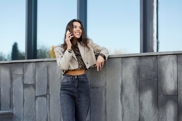 Ritratto di una donna moderna che parla su un telefono cellulare bella ragazza all'aperto nei pressi di un edificio moderno