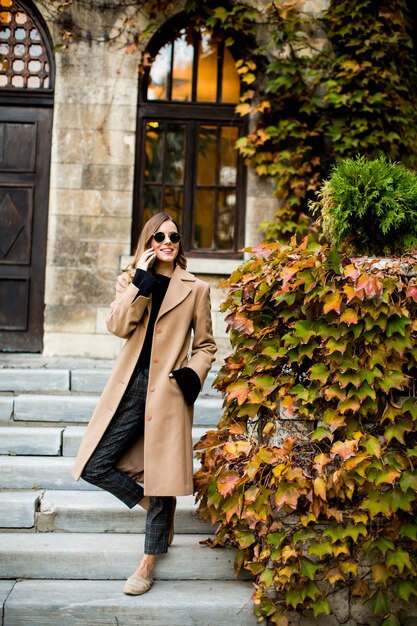 Portrait of modern woman using mobile phone at autumn outdoor