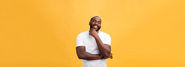 Portrait of a modern young black man smiling with arms crossed on isolated yellow background