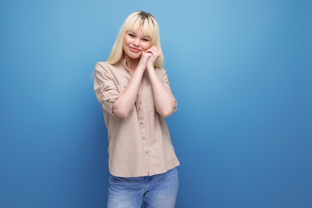 Portrait of a modest shy blond european young woman in a shirt with emotions of happiness