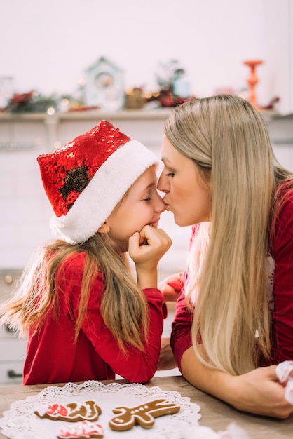 Portrait of mom and daughter. A mother kisses her teenage girl in the nose in the kitchen