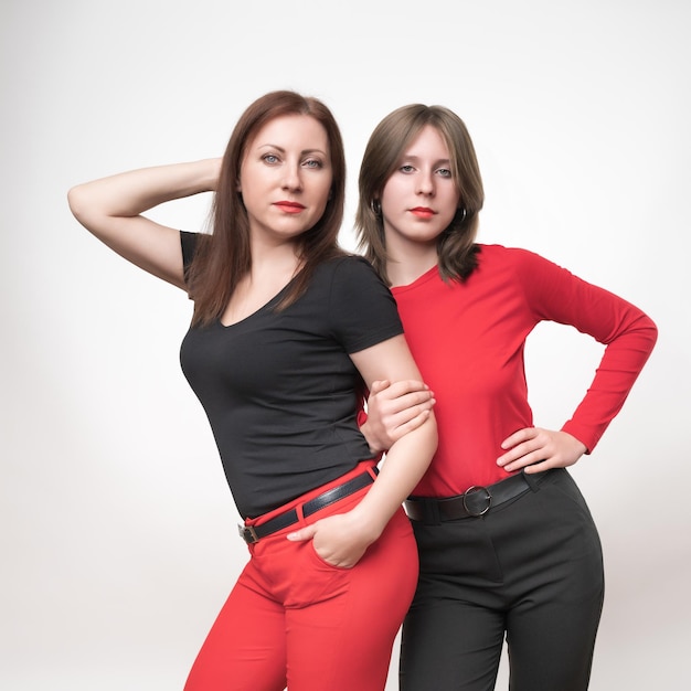 Portrait mom and teenager daughter standing and looking at camera curving pose on white background