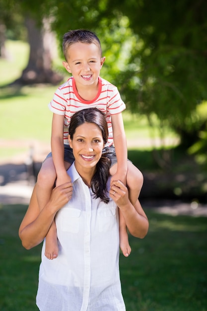 Portrait of mother carrying son on her shoulder in park