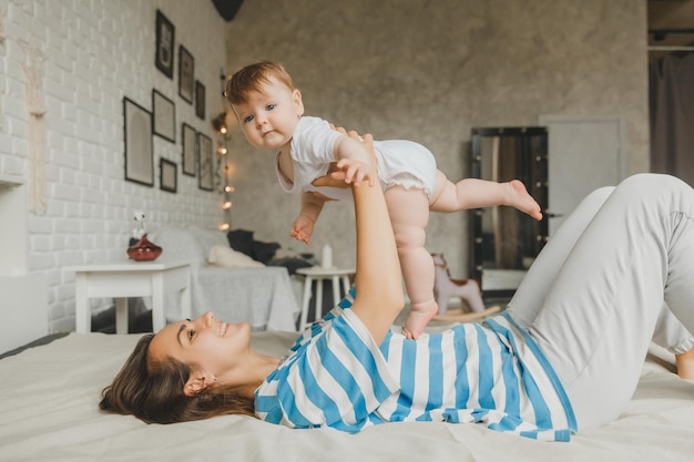 Portrait of mother and child laughing and playing on bed at home