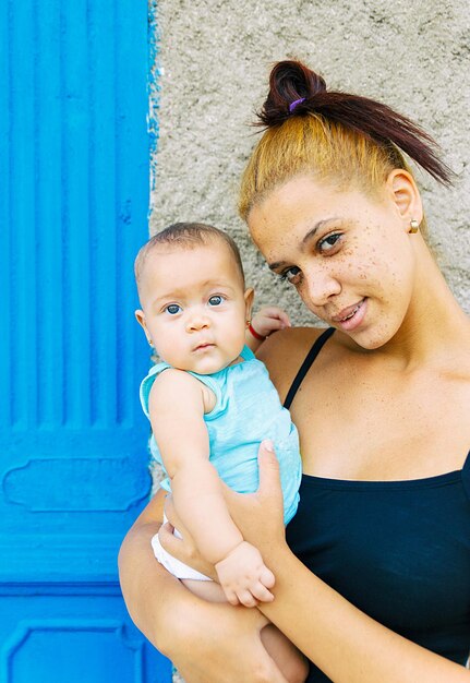 Portrait of mother and daughter against wall