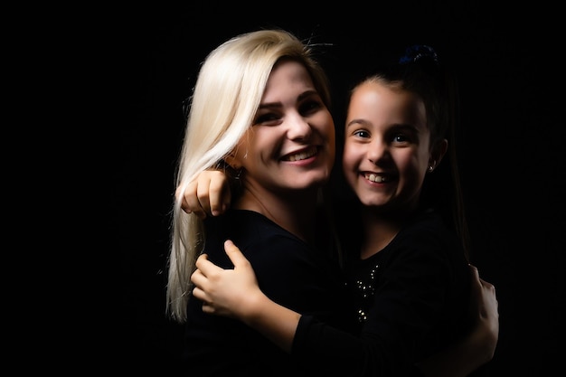 portrait of mother and daughter on black background.