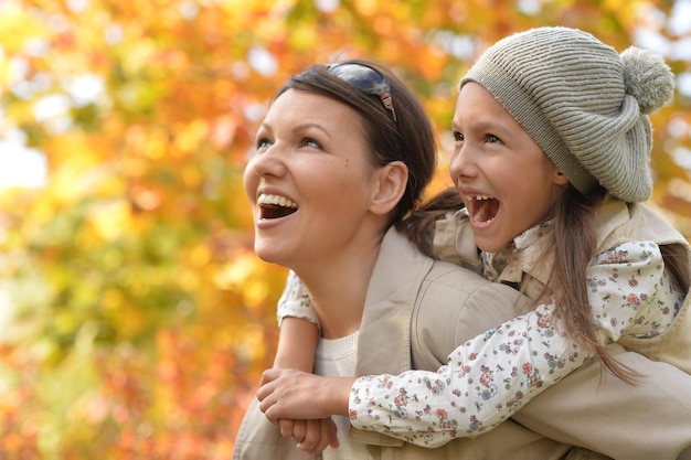 Portrait of mother and daughter hugging in autumn park