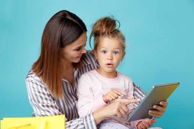 portrait of mother and daughter in pajamas with tablet