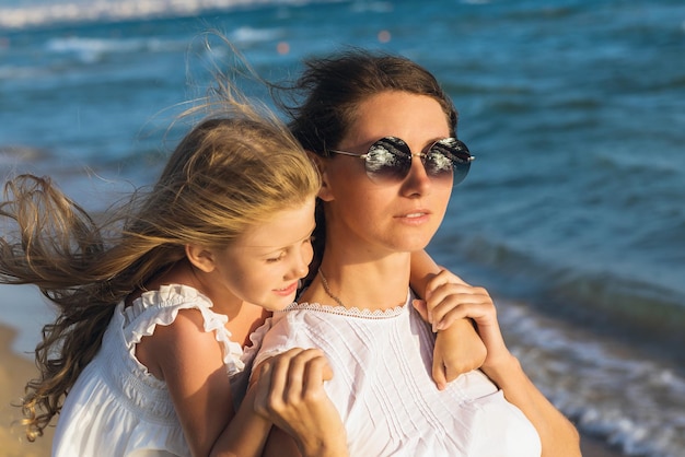 Портрет матери и дочери на берегу моря теплым солнечным вечером