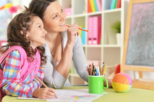 Portrait of mother and daughter sitting at table