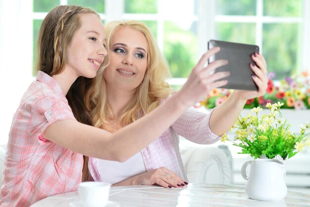 Photo portrait of mother and daughter using tablet