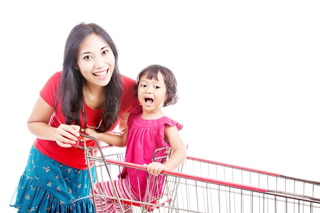 Portrait of mother and daughter with shopping cart against white background