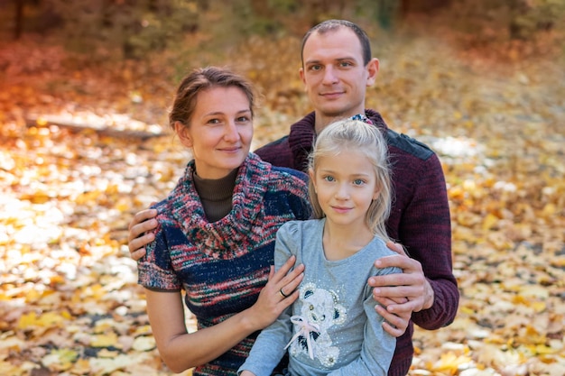 Photo portrait of mother father and daughter on a background of yellow autumn forest