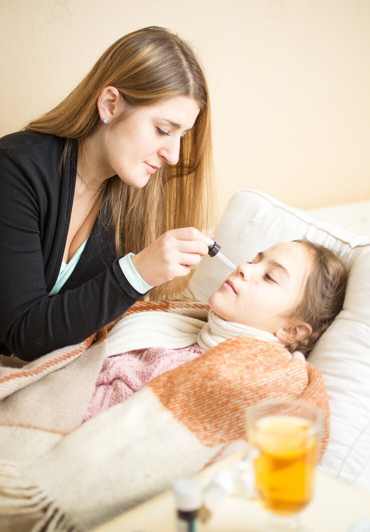 Photo portrait of mother giving nasal medicines to sick daughter lying in bed