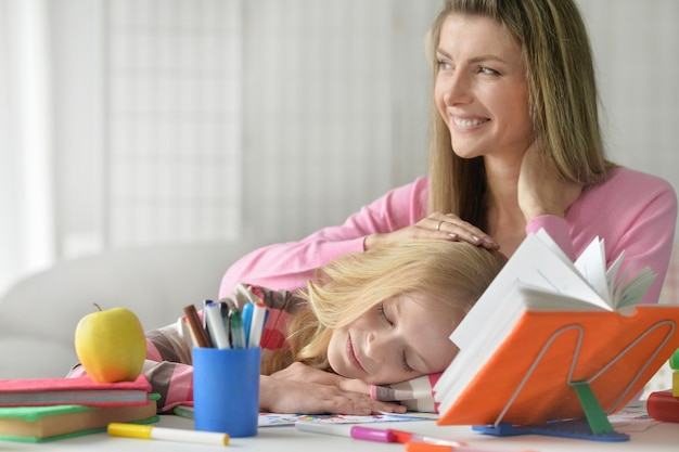 Portrait of mother helping her little daughter with homework