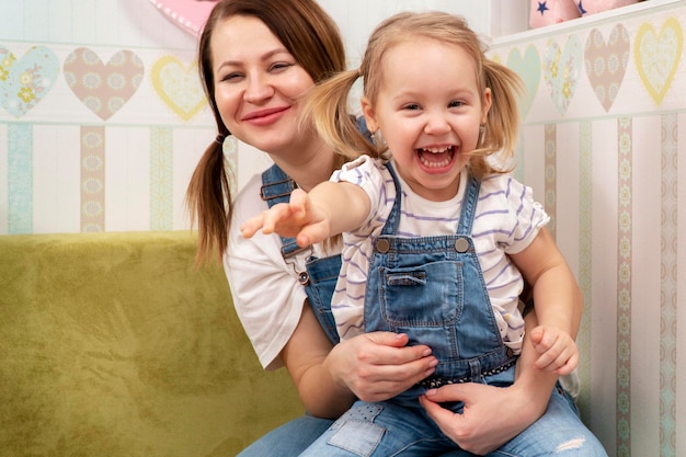 portrait of mother and laughing daughter pulling hand to camera