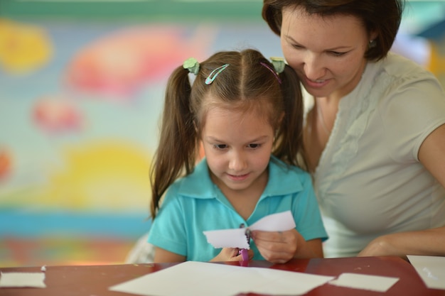 Photo portrait of a mother with child girl  cutting together