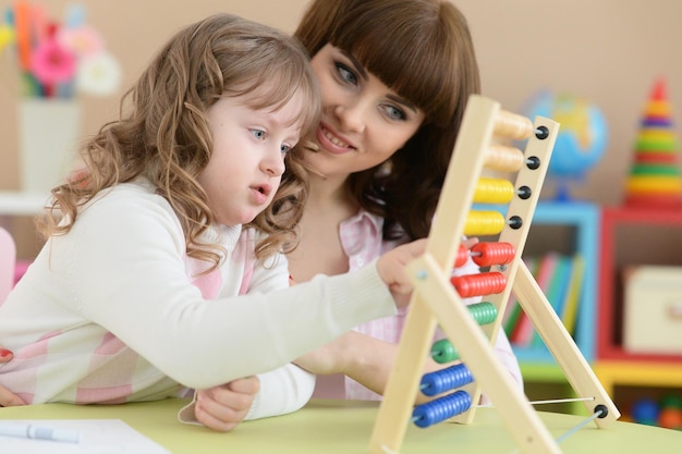 Portrait of mother with little daughter counting with abacus