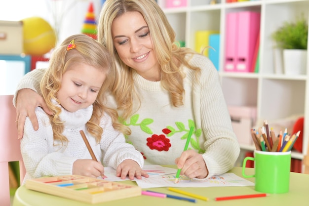 Portrait of a mother with little daughter drawing together