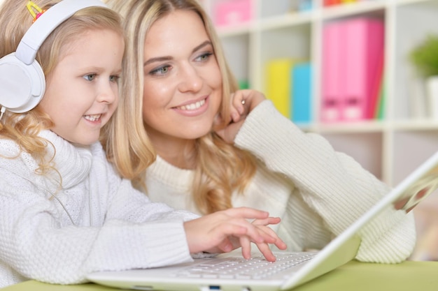 Portrait of a mother with little daughter using laptop