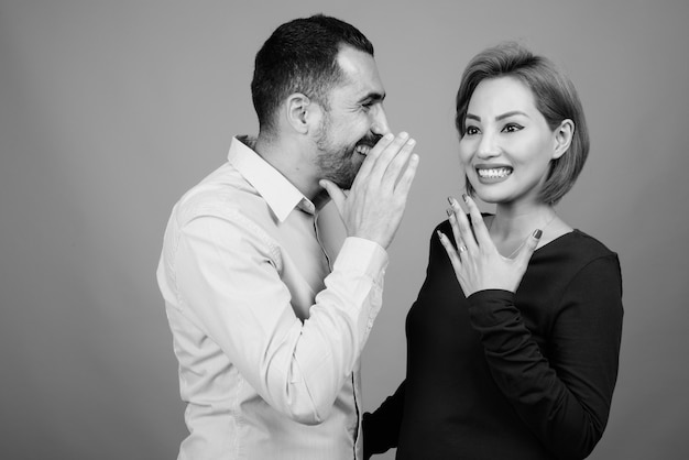 Portrait of multi ethnic couple together and in love on gray in black and white