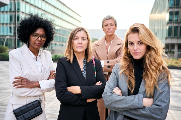 portrait multiethnic business women diverse ages posing looking serious with arms crossed outdoors