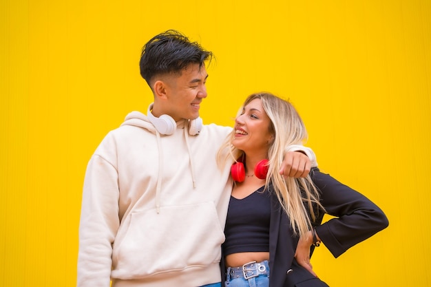 Portrait of a multiethnic couple of Asian man and Caucasian woman on a yellow background knowing looks