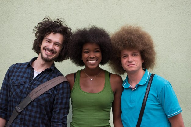 Photo portrait of multiethnic group of happy three friends in casual wear standing and laughing