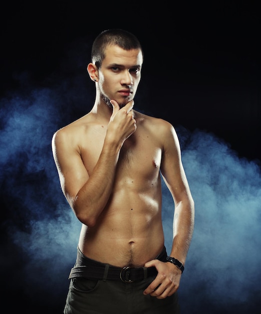 Portrait of a muscular male model against dark background with