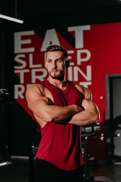 Портрет мускулистого мужчины в шортах и красной футболке позирует